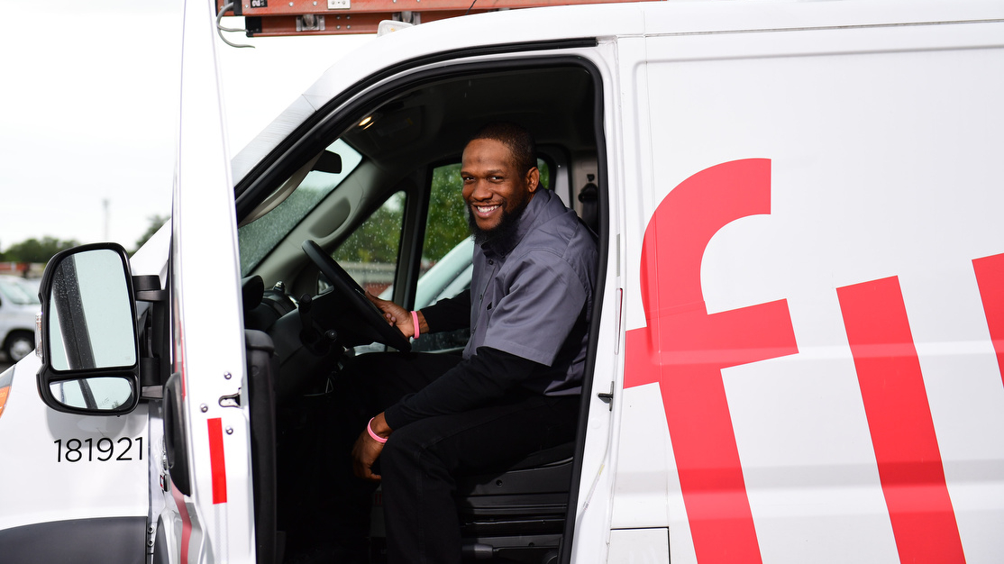 An Xfinity technician sits in the driver's seat of his van.