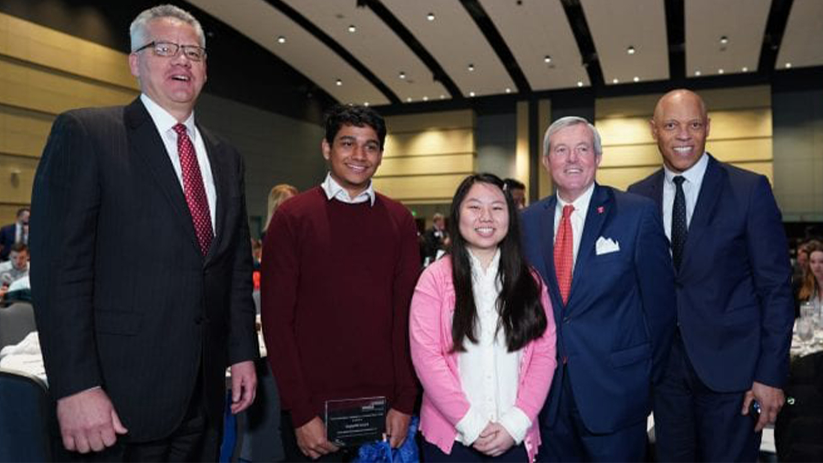 Two college students being honored by employees and local officials.